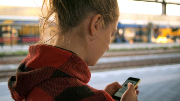 Eine Junge Frau steht am Bahnhof und schaut auf ihr Smartphone (Quelle: Daria Nepriakhina / unsplash.com) Eine Junge Frau steht am Bahnhof und schaut auf ihr Smartphone